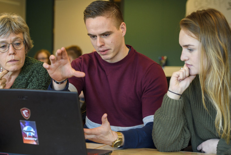 Drie mensen achter laptop