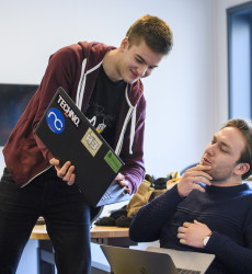Een student die een andere student iets laat zien op zijn laptop