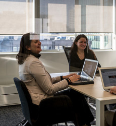 Drie mensen die lachend rond een tafel zitten met laptops