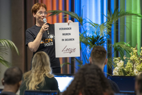 Vrouw houdt bord vast "verander muren in deuren" van Loesje