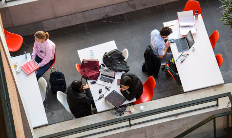studenten zitten in een ruimte op rode stoelen