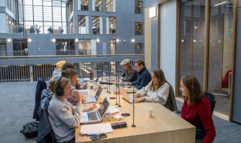 Studenten met laptops aan een gezamenlijke tafel in een instelling