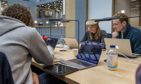 Drie studenten werken in de bilbiotheek van de UvA op hun laptops.