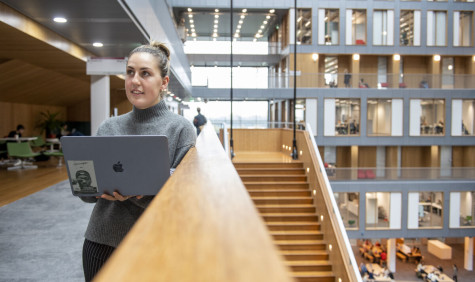 studente staat met laptop in de hal van de VU amsterdam
