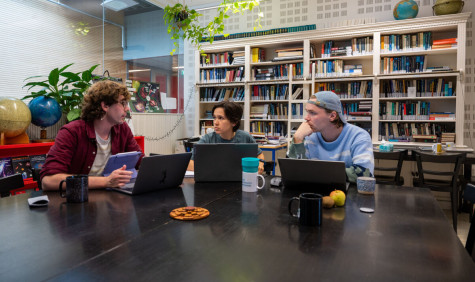 drie studenten in gesprek aan tafel achter hun laptop