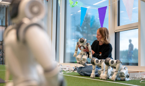 Studente zit op de grond en is met een robot aan het werk