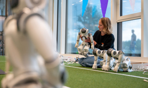 Studente zit op de grond en is met een robot aan het werk