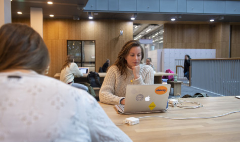 Studente op laptop aan het werk in de hal van de VU