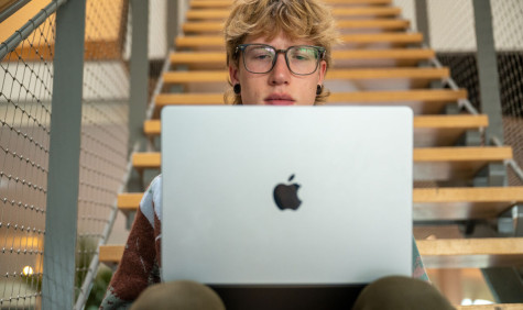 student zit op de trap en werkt op zijn apple laptop