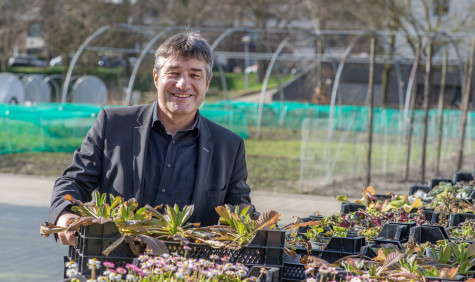 Patrick Cramers heeft een bak planten in zijn handen en lacht in de camera