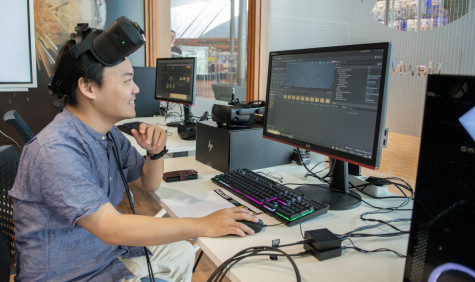 Man kijkt naar beeldscherm met VR-bril op zijn voorhoofd