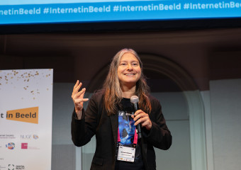 Melanie Rieback met microfoon op podium