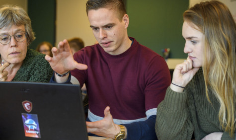 Twee jonge onderzoekers met een oudere dame samen achter een laptop