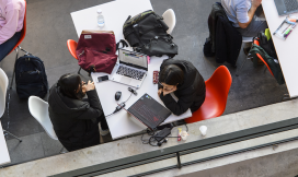 Bovenaanzicht van studenten achter computer met mobiel