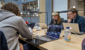 Drie studenten werken in de bilbiotheek van de UvA op hun laptops.