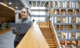 studente staat met laptop in de hal van de VU amsterdam