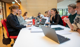 6 studenten werken in de bibliotheek samen aan een tafel