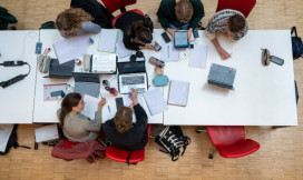 Bovenaanzicht van 6 studenten die samen studeren aan een lange tafel