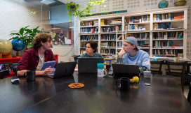 drie studenten in gesprek aan tafel achter hun laptop