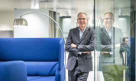 Paul Hillman staat in de gang en leunt tegen een glazen wand