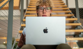student zit op de trap en werkt op zijn apple laptop