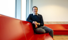 Tom Emery zit en kijkt lachend de camera in