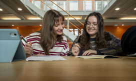 Twee studenten werken aan tafel samen en schrijven iets op
