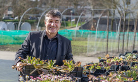 Patrick Cramers heeft een bak planten in zijn handen en lacht in de camera