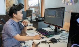 Man kijkt naar beeldscherm met VR-bril op zijn voorhoofd