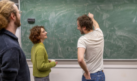 Drie onderzoekers staan voor een schoolbord