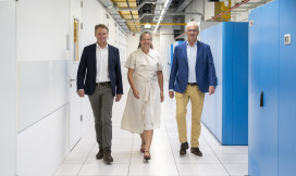 Het SURF-bestuur, Ron Augustus, Hans Louwhoff en Pauline Satter komen aanlopen in een datacenter