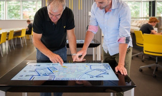Oudere man met jongere man kijkend naar interactief scherm