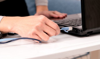 Close-up van vrouw die internetkabel in laptop steekt