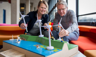 medewerkers van instelling kijken naar een mock up van windmolens