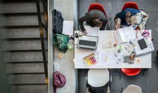 Studenten aan een tafel achter hun laptops