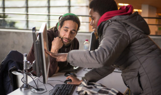 Een vrouw wijst iets aan op een computerscherm waar een man naar kijkt