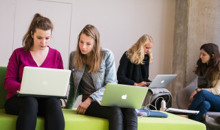 Twee studentes met laptop op schoot op een bankje