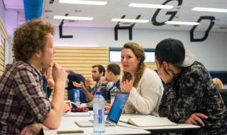 Studenten in gesprek aan tafel met laptop