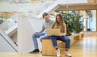 Twee studenten in een open hal met een laptop