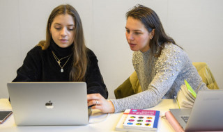 Leerlingen achter laptop met boeken bij Fontys Eindhoven