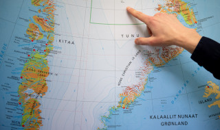 Van Kampenhout wijst met zijn vinger op een landkaart van Groenland
