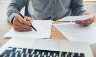 Persoon schrijft op papier, ook toetsenbord in beeld
