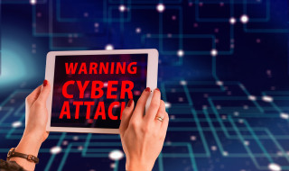 Een vrouw houdteen tablet vast met daarop de tekst 'Warning cyber attack' 