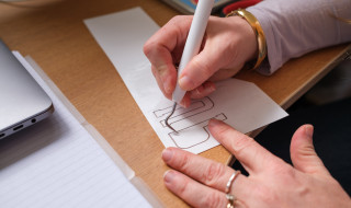 Handen van Sarah Coombs snijden papieren letters uit