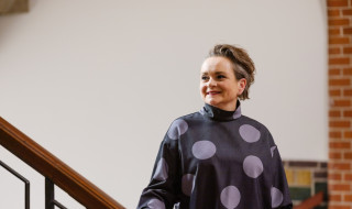 Alexandra van Huffelen stands next to a staircase and looks past the camera, smiling