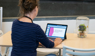 Astrid van Wesenbeeck werkt aan tafel met haar laptop