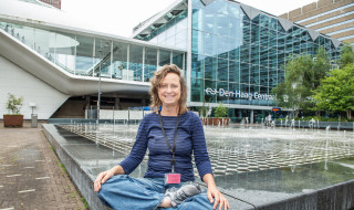 Astrid van Wesenbeeck zit in kleermakerszit voor Den Haag Centraal