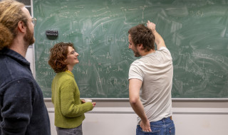 Drie onderzoekers staan voor een schoolbord