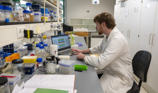 onderzoeker werkt op laptop in lab