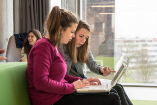 Twee studentes kijken samen naar een laptop